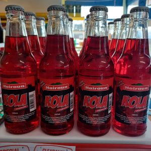 A red coloured drink called Kola in a glass bottle.